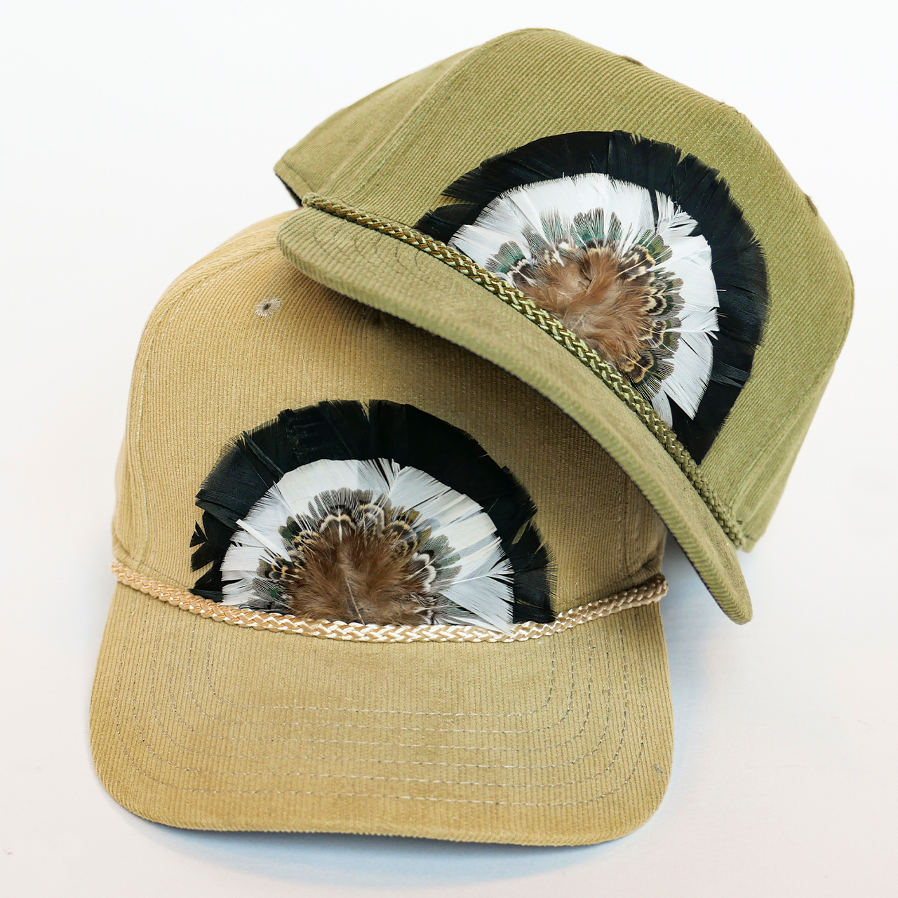 Two caps with feather designs on a light background