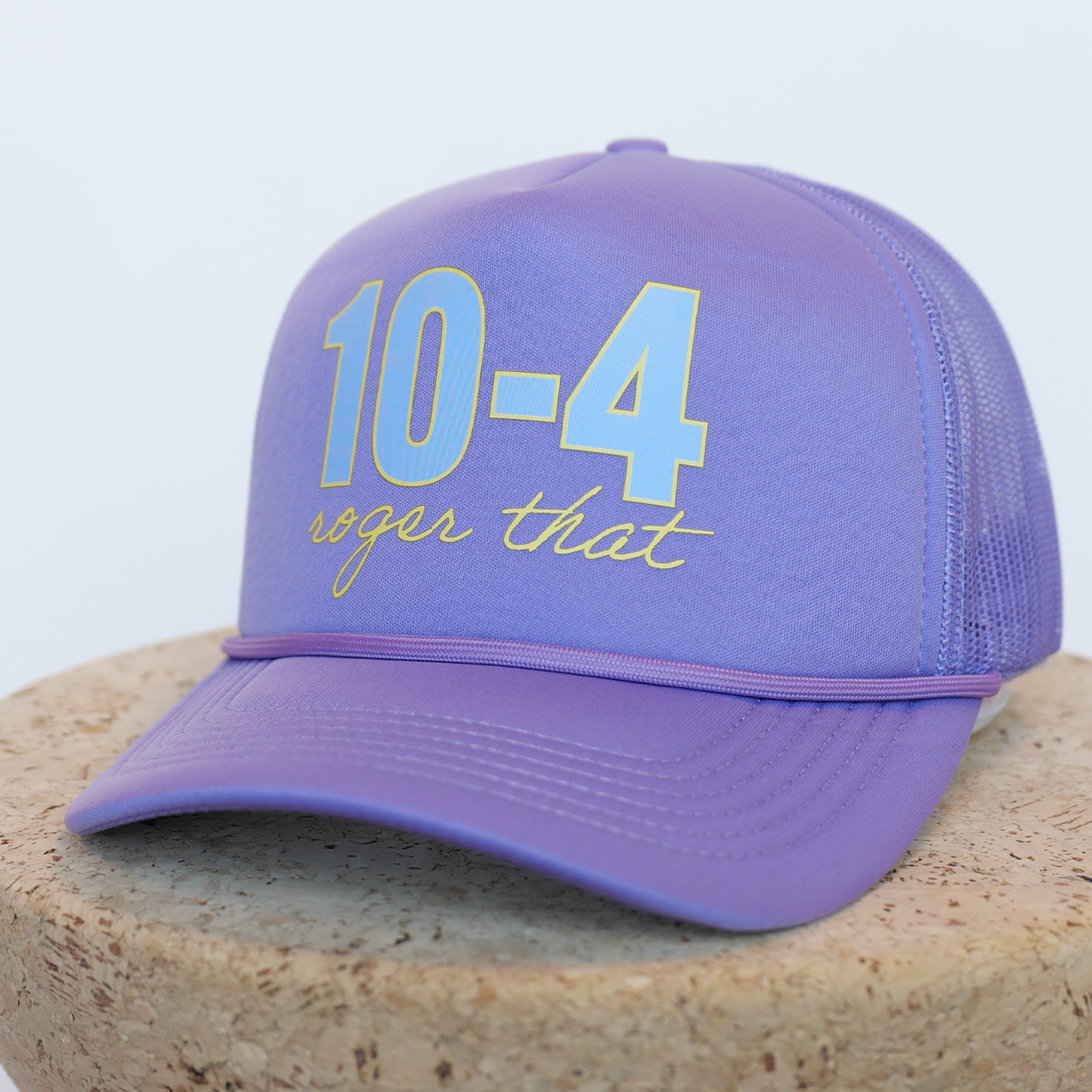 Purple cap with '10-4 roger that' text on a stone surface
