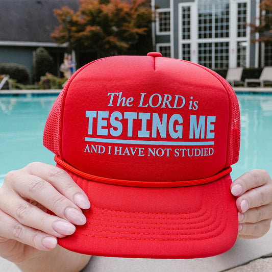 Red cap with text held by a person by a poolside