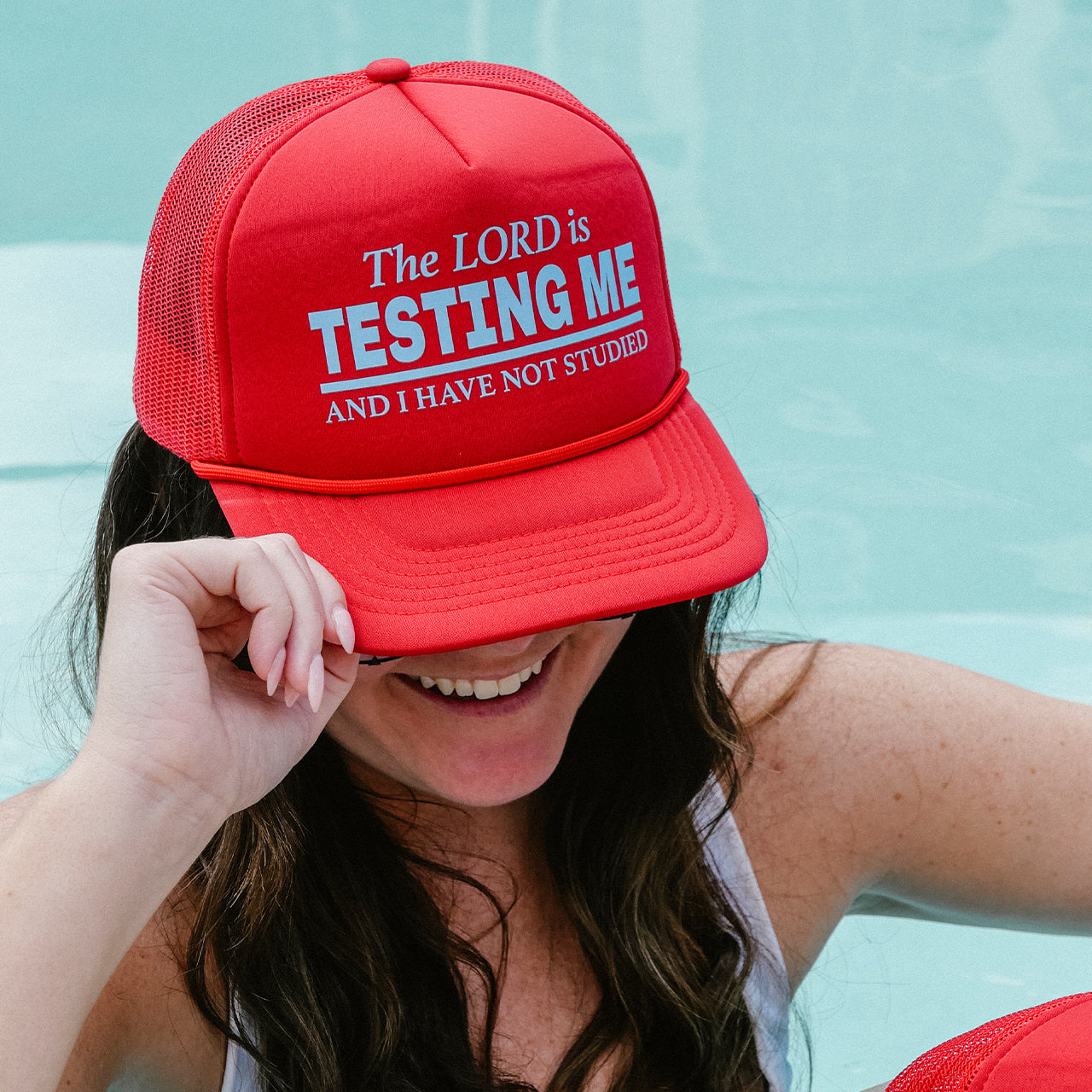 Person wearing a red cap with text by a pool