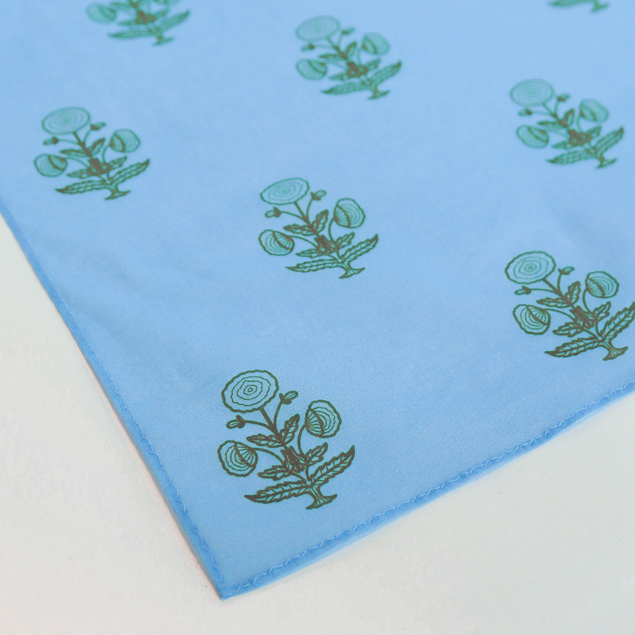 Blue fabric with green floral patterns on a white background