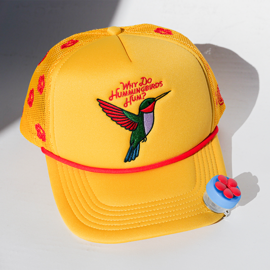 Yellow cap with hummingbird design and text on a white background