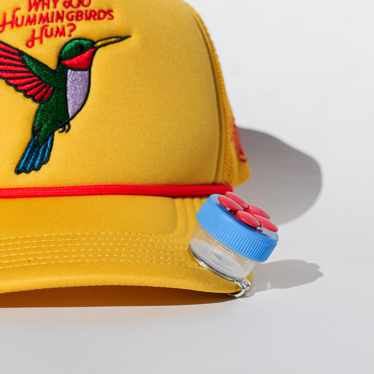 Yellow cap with a hummingbird design and text, featuring a bottle cap on a light background