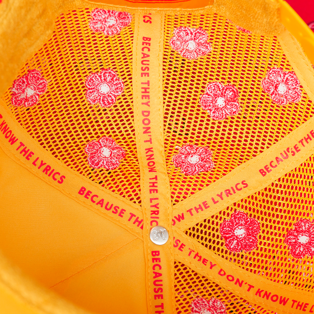 Close-up of a yellow cap with red floral patterns and text.