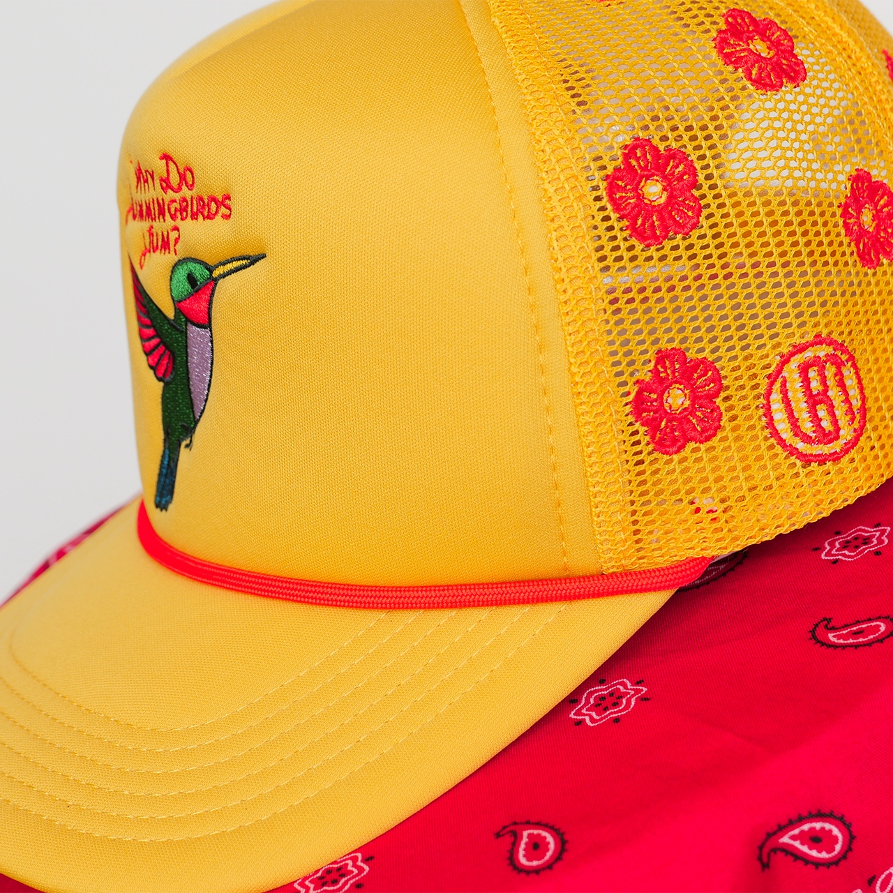 Yellow cap with red floral patterns and a bird design on a white background